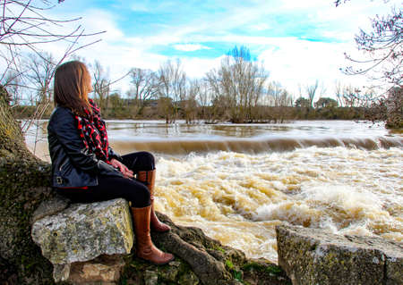 Girl looking at the rising riverの写真素材