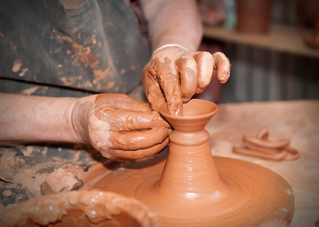 potter working on the lathe with a lump of clayの写真素材