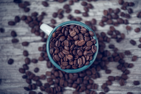 coffee beans without grinding into Cup and on wooden tableの写真素材