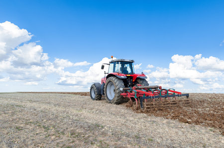 agricultural machinery in the foreground carrying out work in the fieldの写真素材