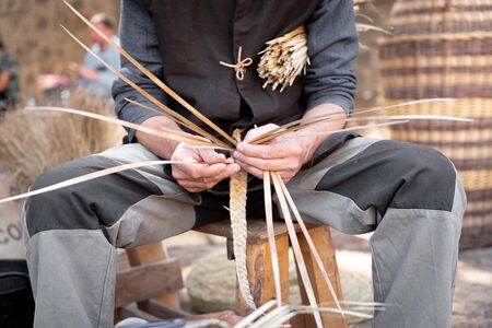 wicker craftsman working with his hands in the manufacture of a basketの写真素材