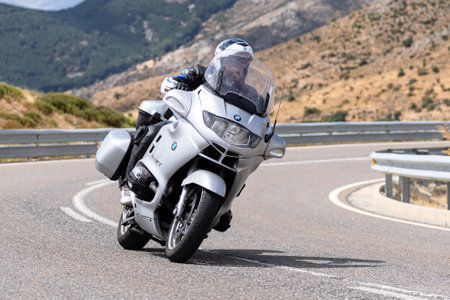 young man driving his motorcycle on a bend on the road, photography on sunny day in the foreground. Photograph captured during the month of August 2021 in the province of Avila, Spainのeditorial素材