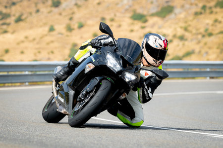 Man on motorcycle carving a tight bend in Puerto de Navalmoral, Ãvila, August 2023のeditorial素材
