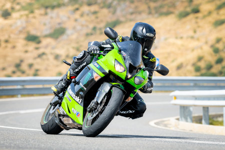 Man on motorcycle carving a tight bend in Puerto de Navalmoral, Ãvila, August 2023のeditorial素材