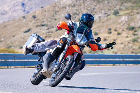 Motorcycle rider riding on a road. Rear view. Horizontal.