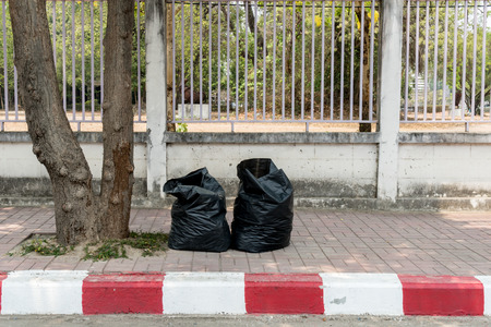 Black garbage bag beside roadの写真素材