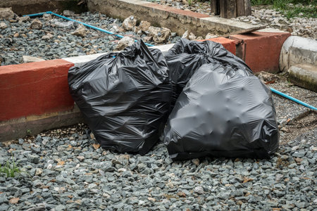 Black garbage bag on gray gravel sidewalk