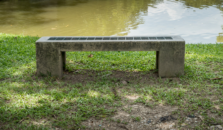 Concrete and iron  bench on green grass in the parkの写真素材