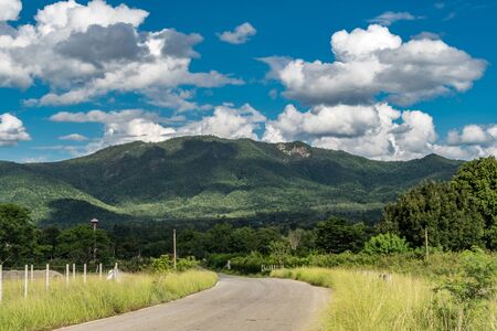 White cloud with blue sky and green mountainの写真素材