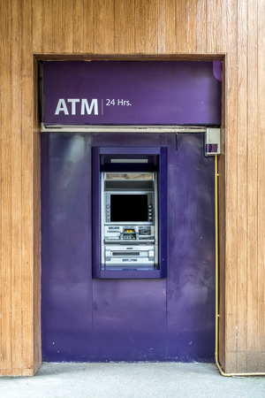 Purple ATM machine on wooden wallの写真素材