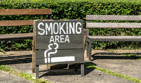 Smoking area sign on wood board with wooden park benchの写真素材