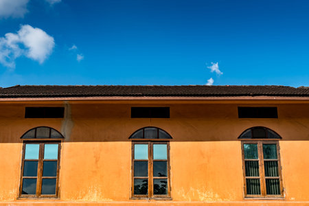 Windows on brown concrete wall with blue sky background
