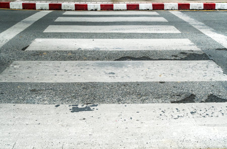 Empty crosswalk on asphalt road with red and white sign on sidewalk curb