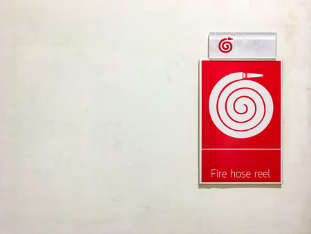Red fire hose reel sign on concrete wallの写真素材