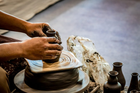Hands shaping clay pot on pottery wheel