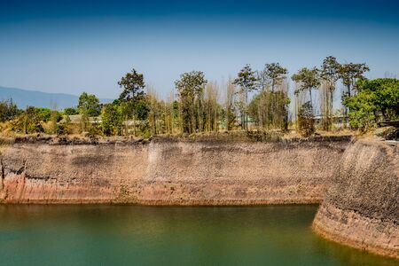 Tropical green forest with green lake on blue sky backgroundの写真素材