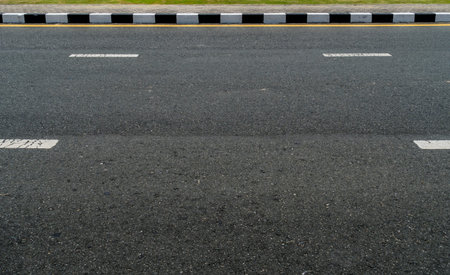 Black and white concrete curb with asphalt road