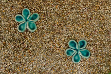 Close up image of concrete with small gravel texture and green ceramic flowerの写真素材
