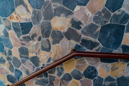 Brown iron stair railing on stone pattern concrete wall