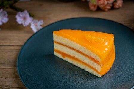 Piece of orange cake on black ceramic plateの写真素材