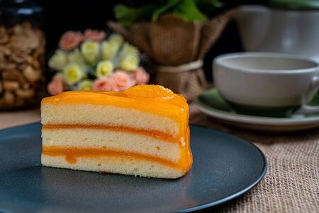 Piece of orange cake on black ceramic plateの写真素材