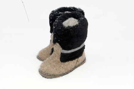 Russian traditional winter felt gray kids boots valenki with fur standing on the snow. Snow poured shoes.の写真素材