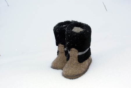 Russian traditional winter felt gray kids boots valenki with fur standing on the snow. Snow poured shoes.の写真素材
