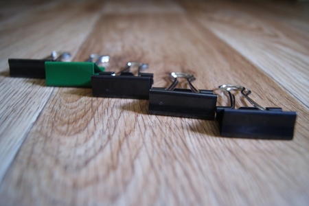 Five binder Paper clips on wooden background in disorder. Perfectionist hell.の写真素材