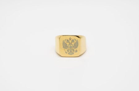 one thick men's gold signet ring with a picture of the double-headed eagle isolated on white backgroundの写真素材