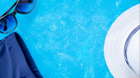Bottle of sunscreen cream or lotion with a sunglasses flat lay on the blue background with copy...