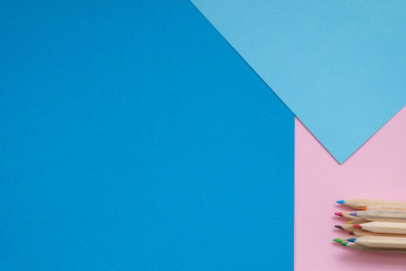 Multi-colored pencils on a colorful pink and blue paper background with colorful pencils . A pile of...