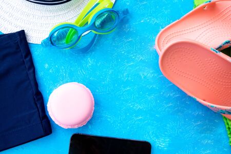 Summer accessories. Glasses, swimming trunks and hat on blue textured background. Top view and copy spaceの写真素材