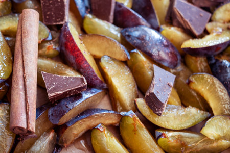 Fresh plum fruit cut into slices, slices with cinnamon sticks, chocolate, cloves. Preparation of ingredients and fruits for making delicious jam.の写真素材