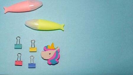 Four binder clips marker and unicorn eraser isolated on blue backgroundの写真素材