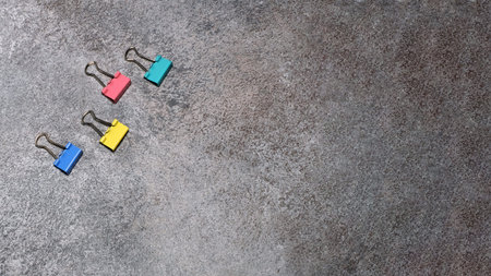 Four binder clips isolated on grey background.