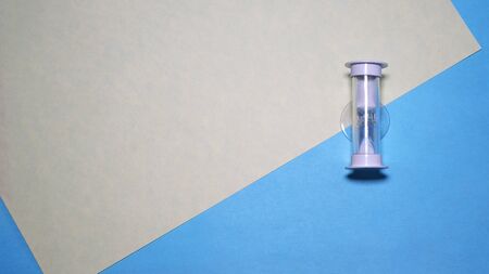 Small hourglass on blue background, top view of minimalistic style compositionの写真素材