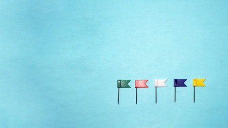 Multicolor plastic flag pins on blue background. five flags needles stationery for fixing something....