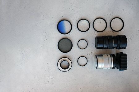 Two lenses and filters to them, adapter rings and a box with flash drives on grey backgrond. Flat lay composition with equipment for professional photographerの写真素材