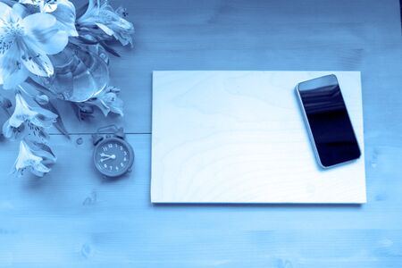 White frame horisontal, mobile phone, alarm clock, pink flower creative blue toned. Flat lay mockup for inspiration quote. Space for youre textの写真素材