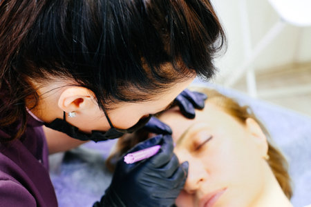 a woman is a master in the process of drawing a sketch of her eyebrows. Using the technique of...