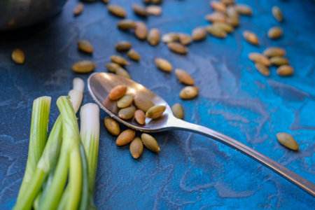 toasted pumpkin seeds and green onions on a blue background, while cooking pumpkin soup. Pumpkin...