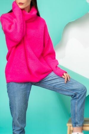 a girl in pink posing on a ragged blue background, shooting an ad or for other use. Girl in sweater and jeans on white backgroundの写真素材