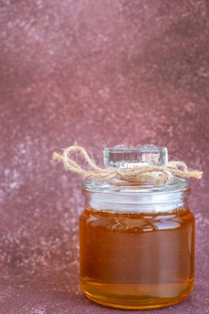 Composition with fresh honey on maroon background. Following center dominant law in white paper background. The concept of honey for saleの写真素材