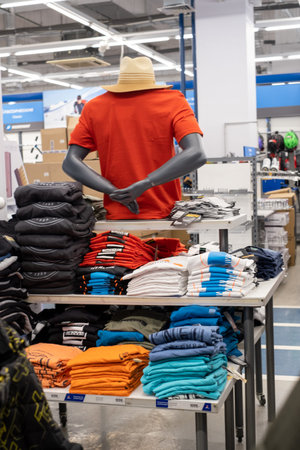15.03.2020 Moscow, Russia. the girl chooses an orange t-shirt from a stack of t-shirts of different...