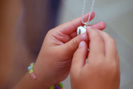Childrens hands holding a beautiful chain with a pendant so closeの写真素材