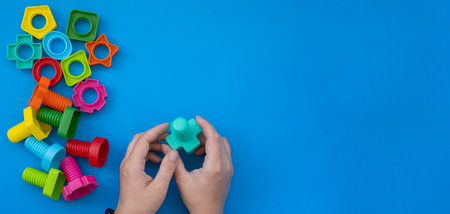 educational constructor for children on blue background, nuts and bolts in the form of geometric shapes. mock up backgroundの写真素材