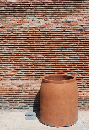 huge clay pot near old brick wallの写真素材
