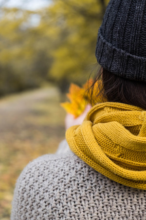 girl in a yellow scarf with maple leaves in her hands in the autumn parkの写真素材