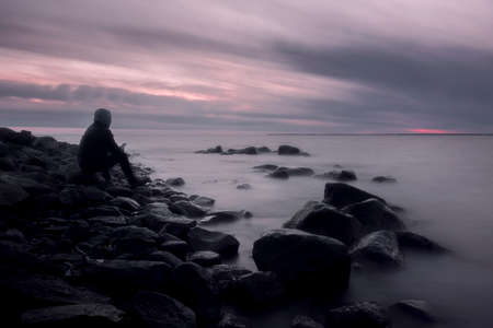 lonely man on the shore of a foggy seaの写真素材