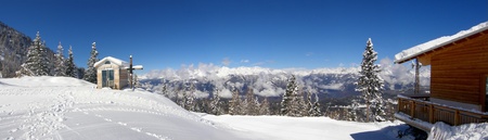 Small snowy chapelle with wooden cross in the mountains panoramaのeditorial素材